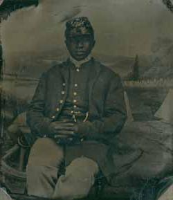 A Black soldier dressed in a Civil War Union uniform, seated and posed facing the camera